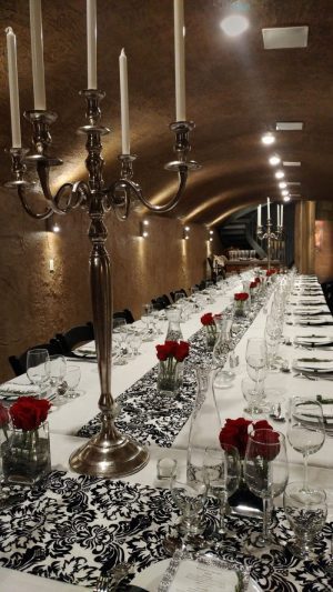 Seven Stones Winery event room set up with a long table with white table cloth, roses in vases, plates and wine glasses